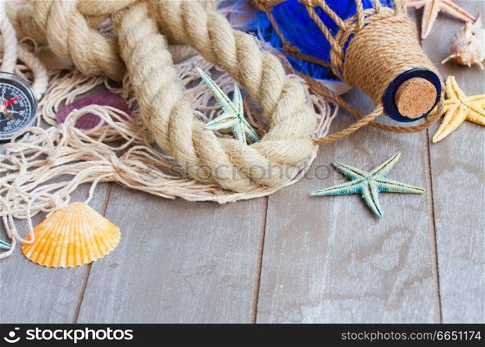 fishing net with marine rope and bottle on gray wooden background. compass on fishing net 