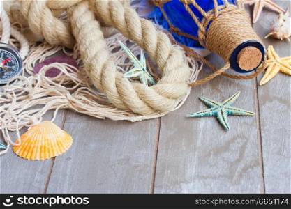 fishing net with marine rope and bottle on gray wooden background. compass on fishing net