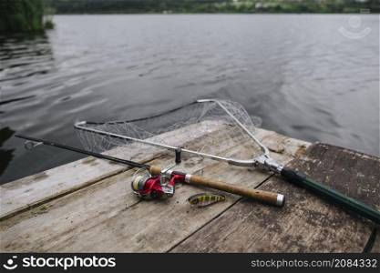 fishing rod with lure net wooden pier idyllic lake