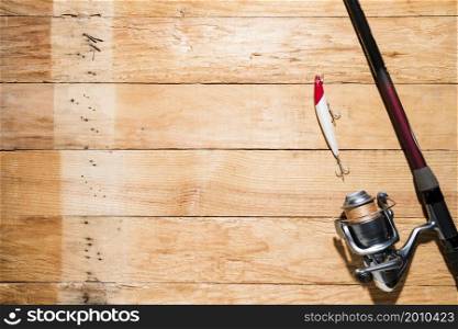 fishing rod with red white fishing bait wooden plank