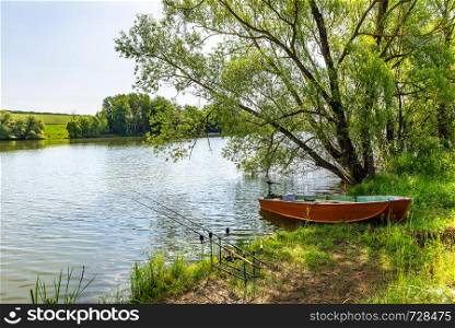 Fishing rods and old boat moored by river. Fishing rods and boat by river