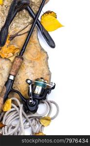 fishing rods with reel on stones with anchor and leafs on white background