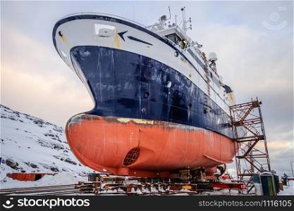 Fishing ships hulls in a dockyard on maintenance during the winter time, port of Nuuk, Greenland