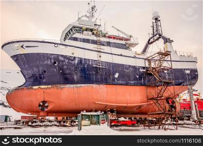 Fishing ships hulls in dockyard on maintenance during the winter time, port of Nuuk, Greenland