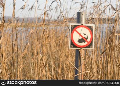 Fishing sign by a river with tall reeds with a caught fishing symbol with a no fishing warning