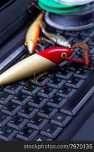 fishing tackles, line, lure, swimbait on dark keyboard a notebook. Prepare fishing to journey, on-line shopping, forums