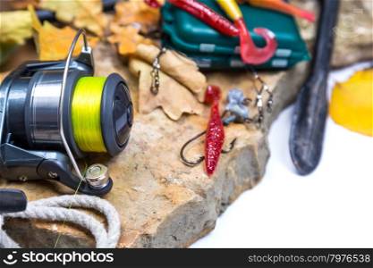 fishing tackles on stones with anchor and leafs on white background