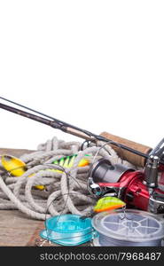 fishing tackles reel, line and wobblers on wooden board with white background