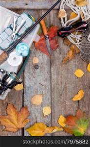 fishing tackles reel, line, wobbler, lure on wooden board with leafs of autumn