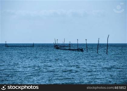 Fishing trap equipment with fishing networks in blue sea waters on blue sky background