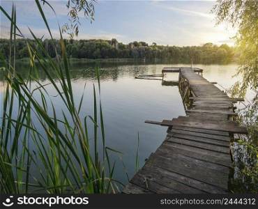 Fishing wooden pier on the lake at sunset. Fishing wooden pier on lake at sunset