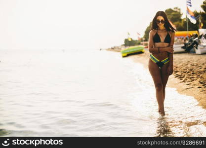 Fit and sporty woman in a swimsuit relaxing on a beach at summer