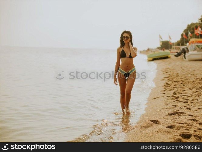 Fit and sporty young woman in a swimsuit relaxing on a beach at summer