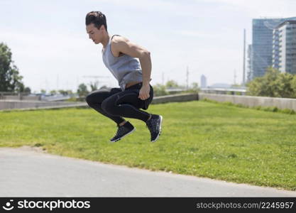 Fit athletic male jumping up on a public park