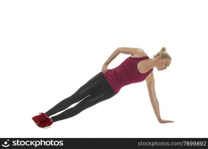 Fit athletic woman working out in a gym balancing at full stretch on her extended arm as she tones her muscles, isolated on white in a health and fitness concept