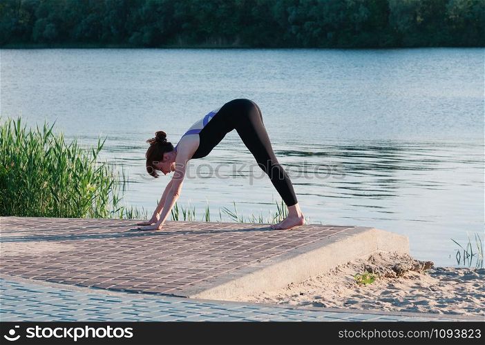 Fit beautiful woman practice yoga, outdoor, summer riverside background. Physical and internal healthcare. Healthy lifestyle, keep fit, weight loss, enjoy life. Strengthen mind and body concept