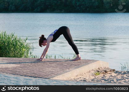 Fit beautiful woman practice yoga, outdoor, summer riverside background. Physical and internal healthcare. Healthy lifestyle, keep fit, weight loss, enjoy life. Strengthen mind and body concept