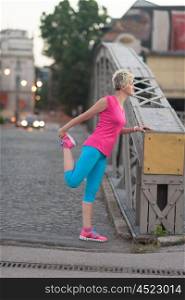 Fit blonde runner woman warming up and stretching before morning jogging