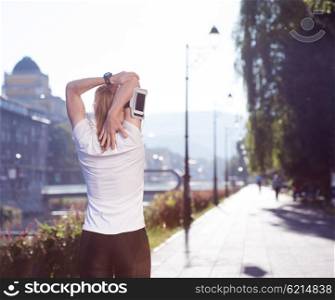 Fit blonde runner woman warming up and stretching before morning jogging