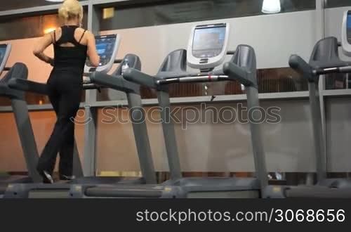 fit blonde woman at the gym running on treadmill
