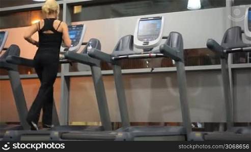 fit blonde woman at the gym running on treadmill
