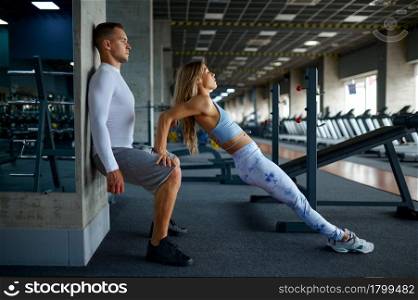 Fit couple doing exercise, fitness training in gym. Athletic man and woman on workout in sport club, active healthy lifestyle, physical wellness. Fit couple doing exercise, fitness training