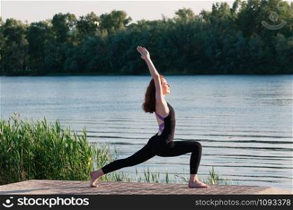 Fit female practice yoga doing stretching exercise pose, outdoor, summer riverside background. Physical and internal healthcare. Healthy lifestyle, keep fit, weight loss, enjoy life and body concept