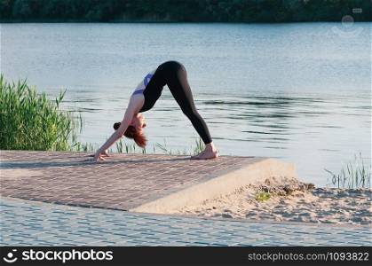 Fit female practice yoga doing stretching exercise pose, outdoor, summer riverside background. Physical and internal healthcare. Healthy lifestyle, keep fit, weight loss, enjoy life and body concept