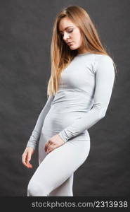 Fit fitness slim woman wearing hot gray sports thermolinen underwear, studio shot on black. Long sleeves top and leggings.. Fit woman in thermolinen underwear,