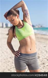 Fit hispanic woman stretches on the beach after a run
