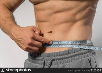 fit man holding measuring tape around waist