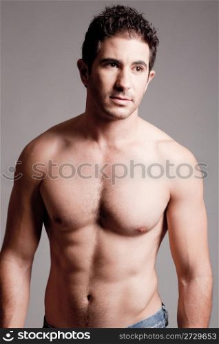 Fit man showing chest and abs on a grey background