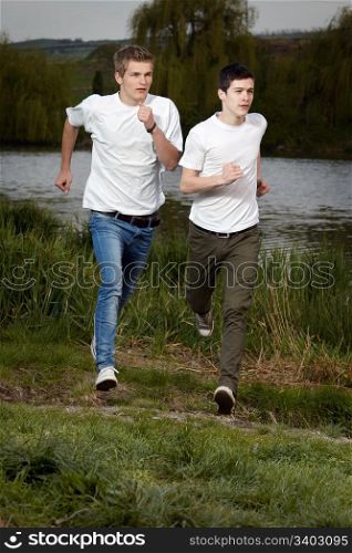 Fit men jogging outdoors beside the lake park