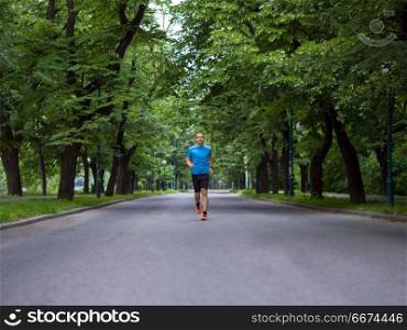 fit muscular male runner training for marathon running on beautiful road in nature.. male runner training for marathon
