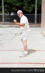 Fit senior man playing racquetball on a public court.