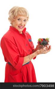 Fit senior woman snacking on a bowl of healthy mixed berries. Isolated on white.