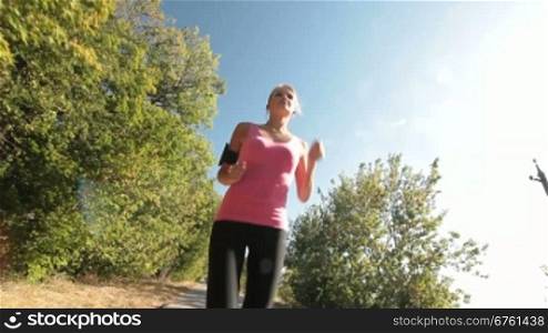Fit sports girl jogging along country road during outdoor workout