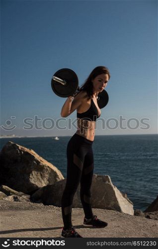 Fit woman lifting weights - Outdoor. Fitness woman with tattoos lifting weights - Outdoor