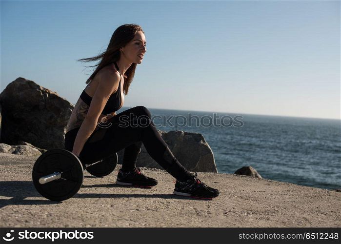Fit woman lifting weights - Outdoor. Fitness woman with tattoos lifting weights - Outdoor