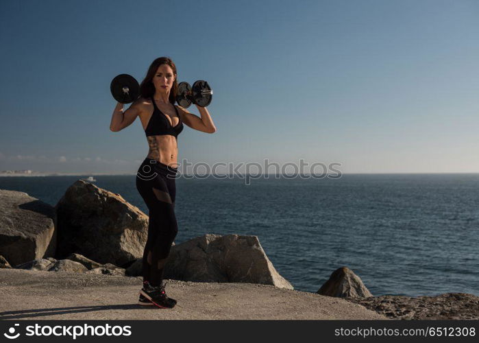 Fit woman lifting weights - Outdoor. Fitness woman with tattoos lifting weights - Outdoor