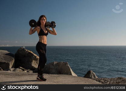 Fit woman lifting weights - Outdoor. Fitness woman with tattoos lifting weights - Outdoor