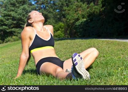 Fit woman resting in the sun after a workout