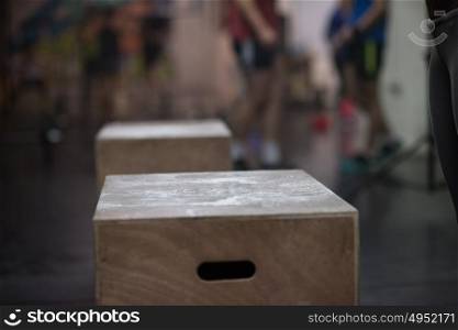Fit young african american woman box jumping at a crossfit style gym. Female athlete is performing box jumps at gym with focus on legs