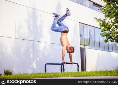 Fit young Caucasian man is doing workout exercise on horizontal bar, outdoors in summer