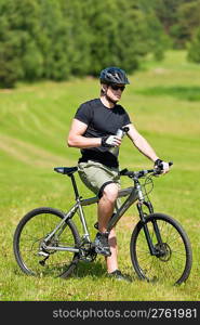 Fit young cycling man relax with water bottle in summer coutryside