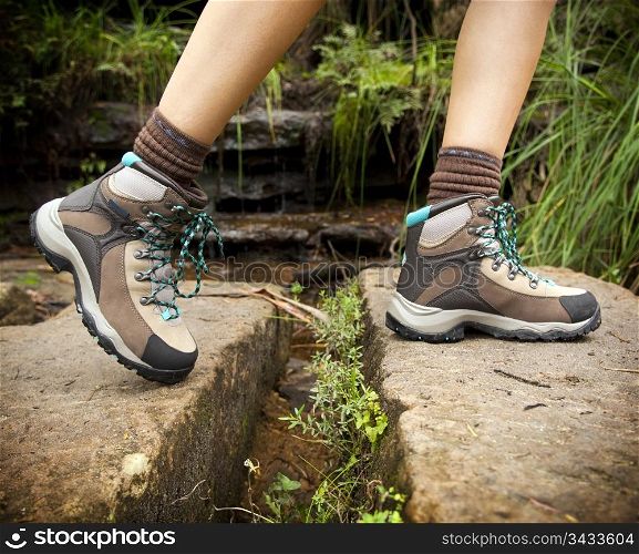 Fit young hiker crosses stone steps in hiking boots