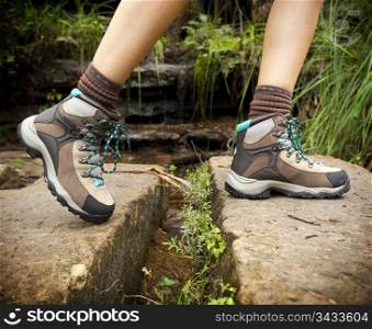 Fit young hiker crosses stone steps in hiking boots