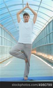 Fit young man practices yoga on the bridge