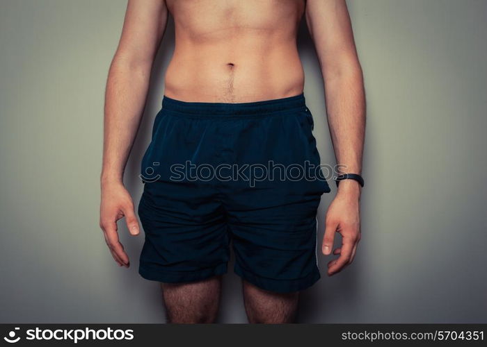 Fit young man with toned stomach standing in relaxed pose