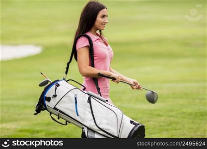fit young woman carrying golf clubs